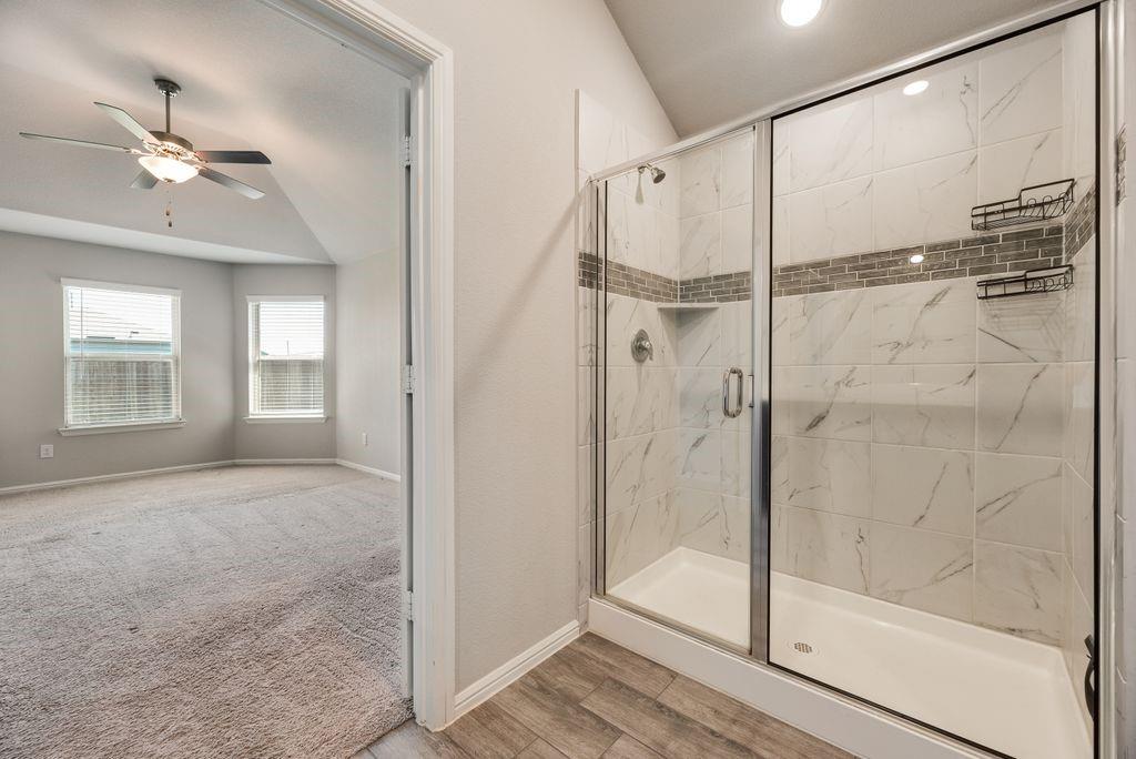 14216 Aberavon Drive Pilot Point, TX 76258 - Photo 14 of 19 Walk-in shower with clear glass enclosure, white tile surround with dark veining, decorative mosaic tile accent, and built-in shelving