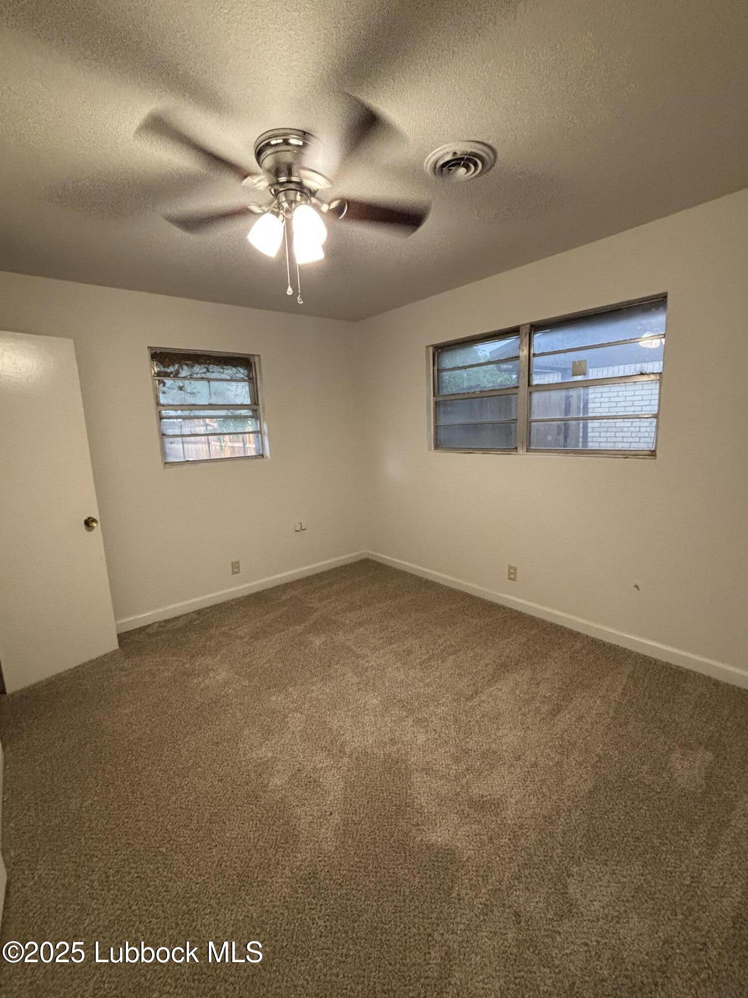 1301 6th Street Shallowater, TX 79363 - Photo 6 of 15 an empty room with a ceiling fan and window