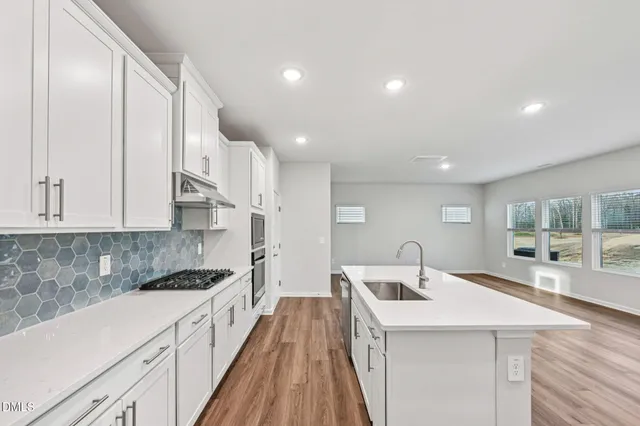 a kitchen that has a lot of white cabinets and wooden floor