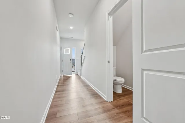 a view of a hallway with wooden floor and a bathroom