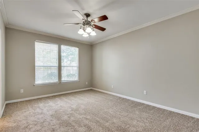 an empty room with chandelier fan and windows