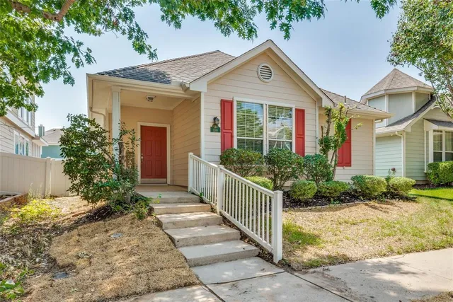 a view of a brick house with potted plants and a large tree