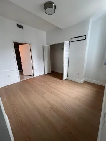 an empty room with wooden floor and mirror