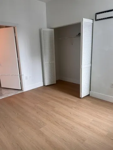 an empty room with a wooden door and mirror