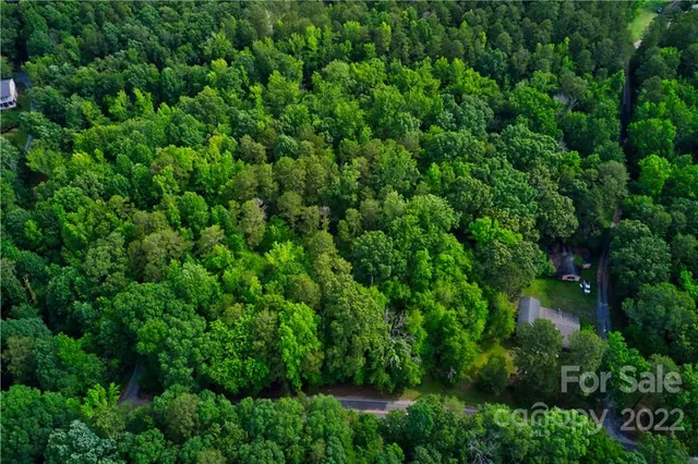 an aerial view of residential house with outdoor space and trees all around