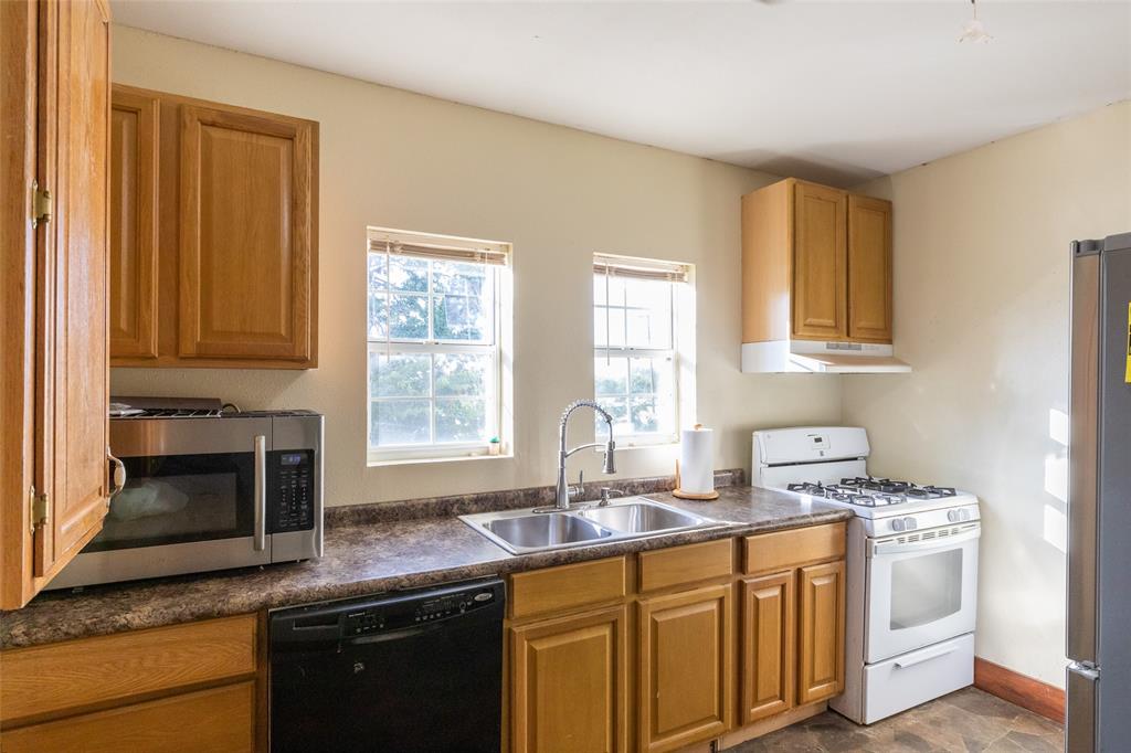 640 Ground Street Moran, TX 76464 - Photo 8 of 35 Kitchen featuring wood cabinetry, laminate countertops, dual basin stainless steel sink, and a white gas range