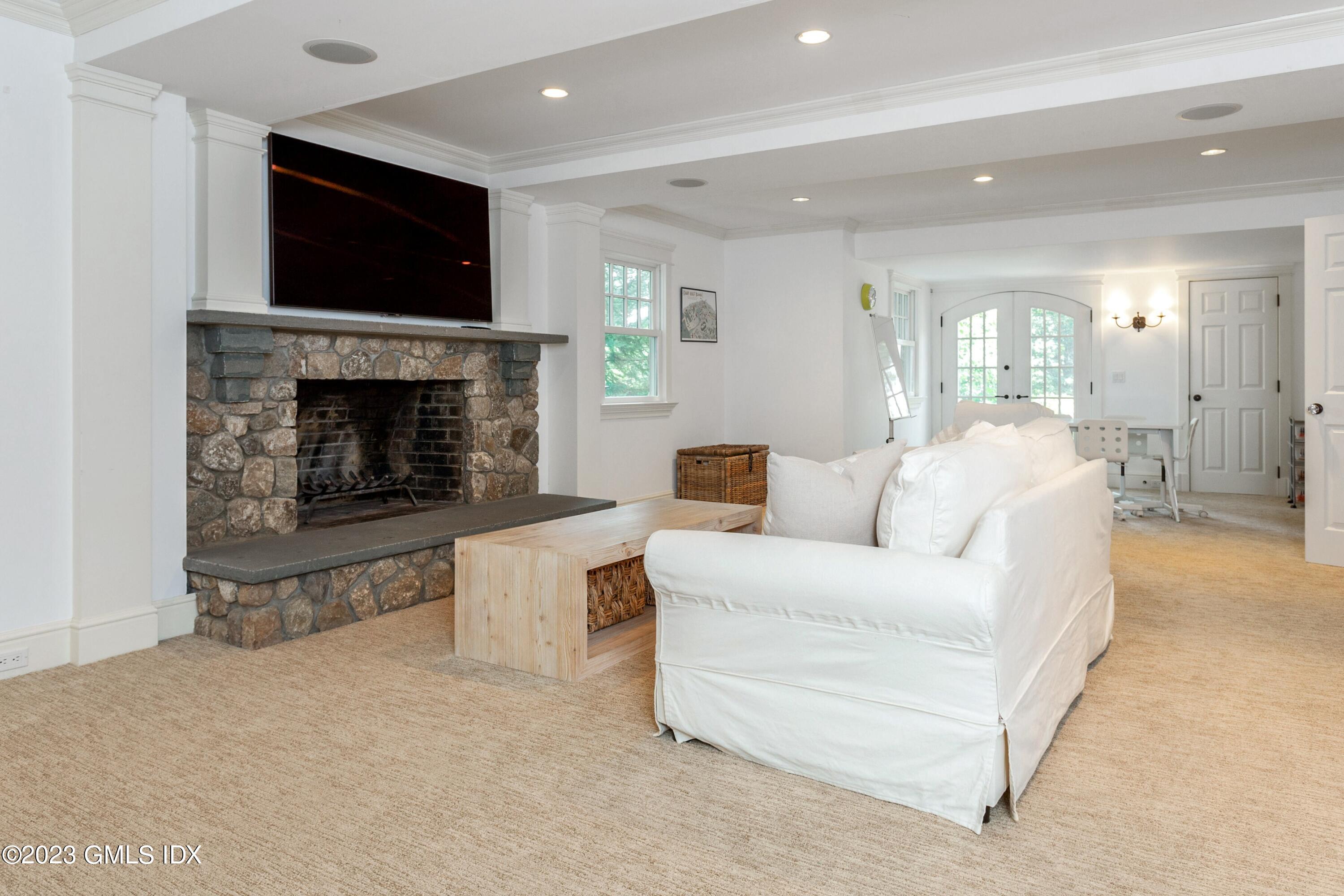 150 Goodwives River Road Darien, CT 06820 - Photo 30 of 39 a living room with furniture a fireplace and a flat screen tv