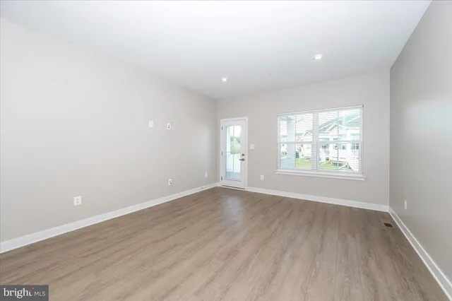 a view of an empty room with wooden floor and window