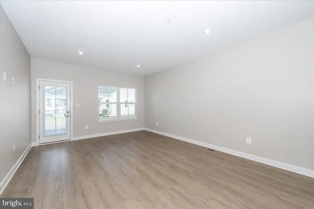 a view of a big room with wooden floor and windows