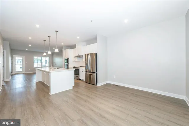 a view of kitchen with kitchen island wooden floor center island and stainless steel appliances
