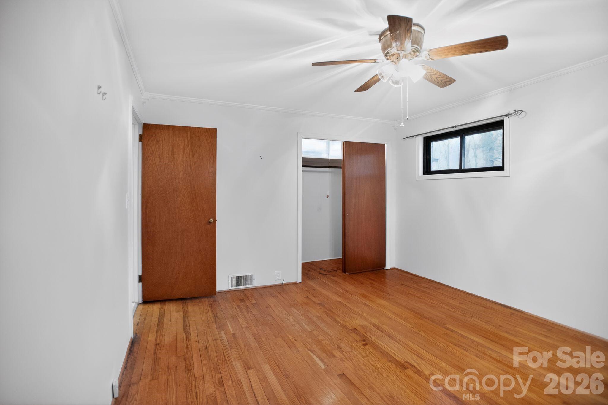 4783 Calico Road Lenoir, NC 28645 - Photo 18 of 44 an empty room with wooden floor chandelier fan and windows