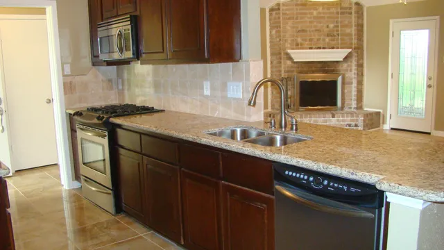 a kitchen with granite countertop a sink stove and cabinets