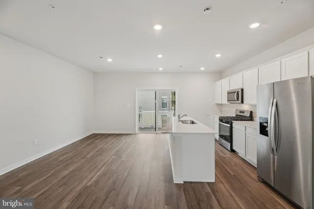 a large kitchen with a wooden floor and stainless steel appliances