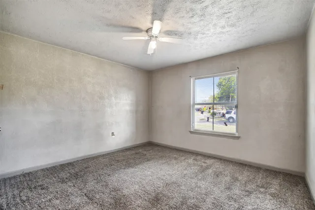 an empty room with windows and ceiling fan
