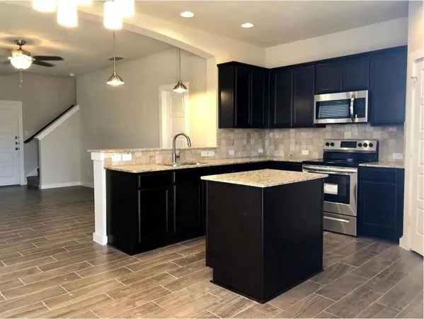 a kitchen with stainless steel appliances granite countertop a stove a sink and a microwave