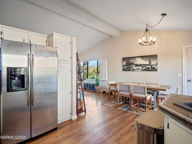 a dining room with wooden floor a chandelier a wooden table and chairs