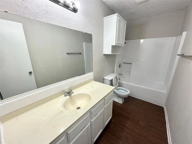 a bathroom with a granite countertop sink a toilet and shower