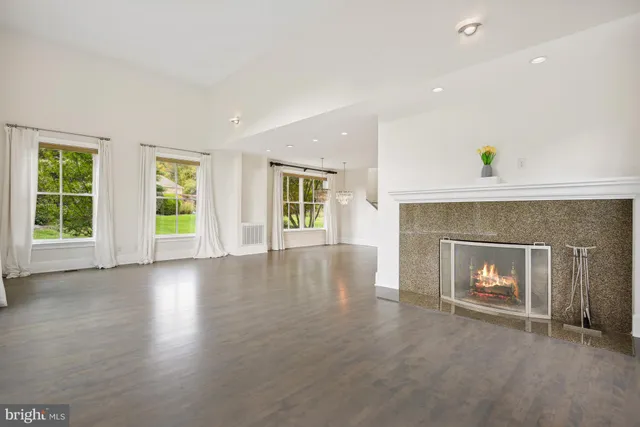 an empty room with windows and fireplace