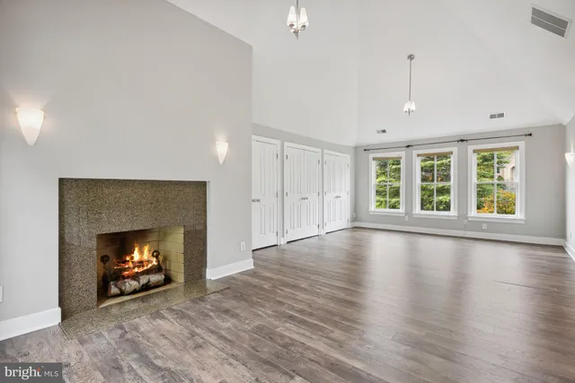 an empty room with wooden floor fireplace cabinet and windows