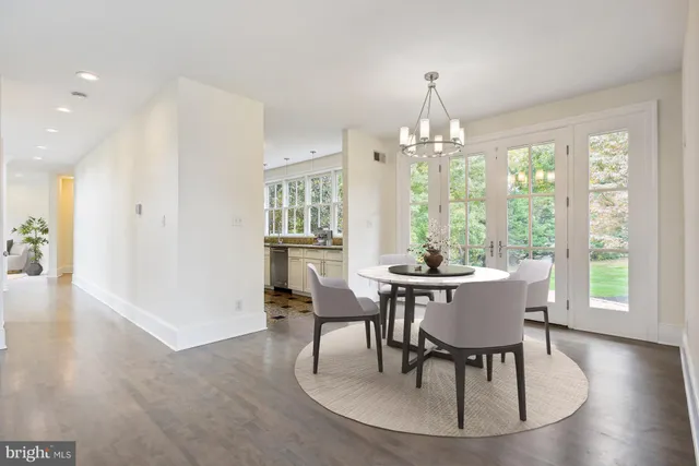 a dining room with wooden floor a chandelier a wooden table and chairs