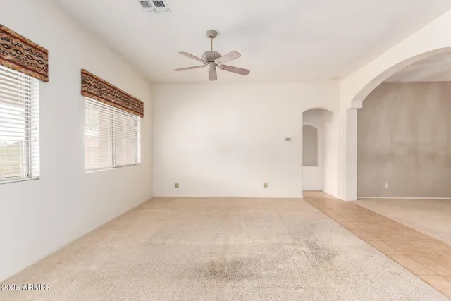 an empty room with windows and fan