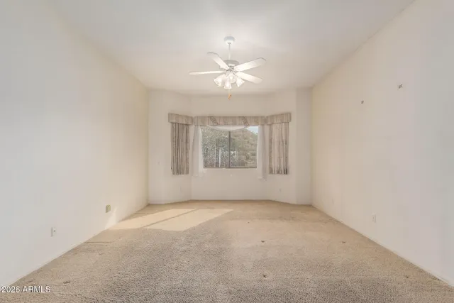 an empty room with a window and a fan