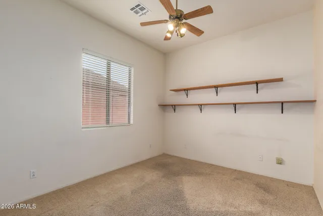 an empty room with windows and fan