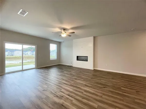a view of an empty room with window and wooden floor