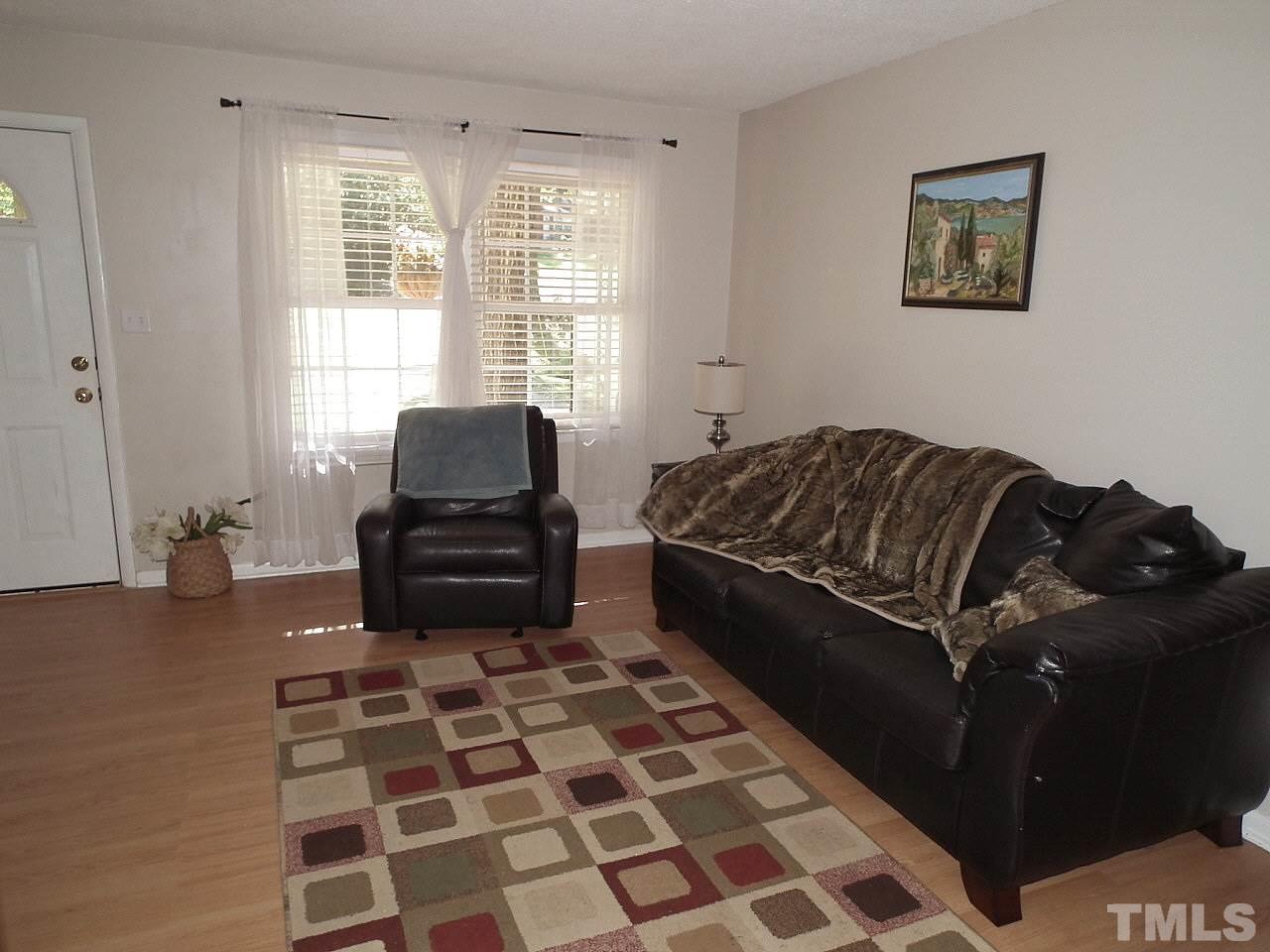 2824 Oak Ridge Court Raleigh, NC 27603 - Photo 8 of 22 a living room with a black white checkered floor with a black white checkered floor next to a window and a chair