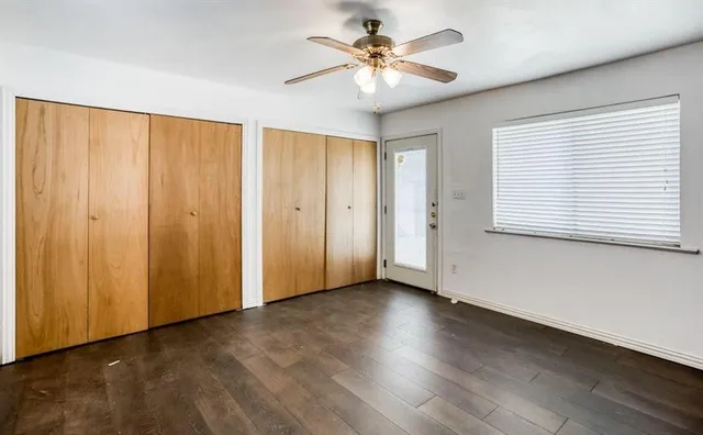 a view of an empty room with a window and wooden floor