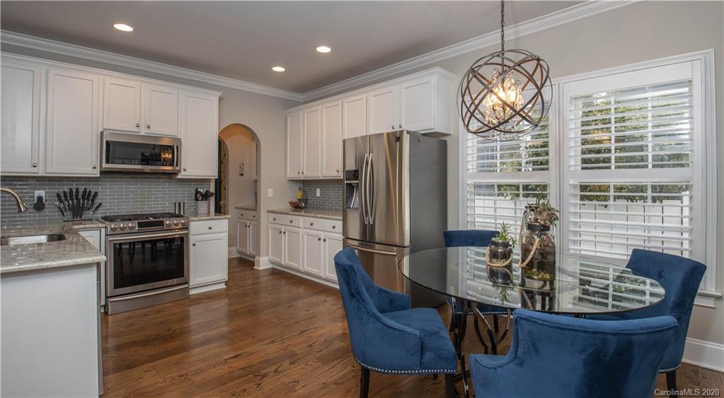 728 Shady Grove Crossing Fort Mill, SC 29708 - Photo 11 of 41 a kitchen with stainless steel appliances granite countertop a stove a refrigerator a kitchen island a sink dishwasher a dining table and chairs with wooden floor