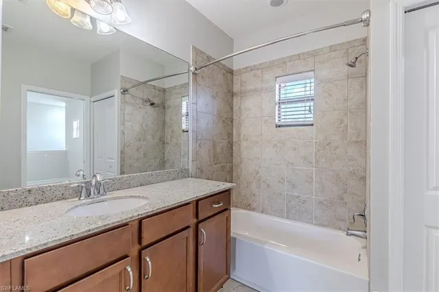 a bathroom with a granite countertop sink a mirror a bathtub and shower