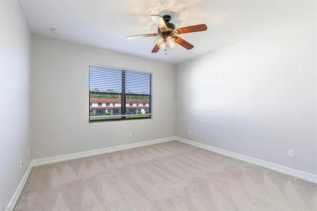 an empty room with windows and ceiling fan