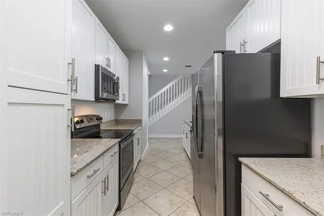 a kitchen with stainless steel appliances granite countertop a refrigerator a stove and a sink