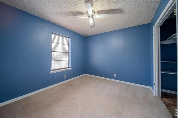 an empty room with windows and chandelier fan