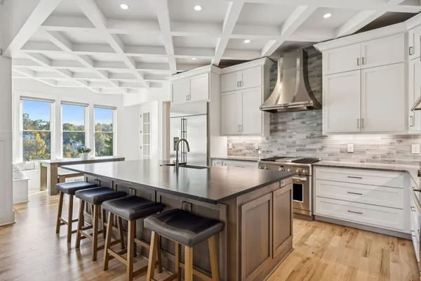 a kitchen with granite countertop a stove chairs and wooden floor