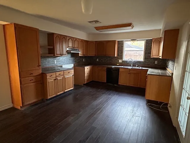 a large kitchen with wooden floors and stainless steel appliances