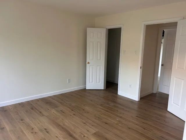 a view of an empty room with wooden floor and closet