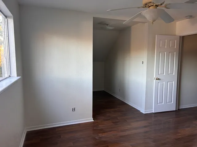 an empty room with wooden floor closet and windows