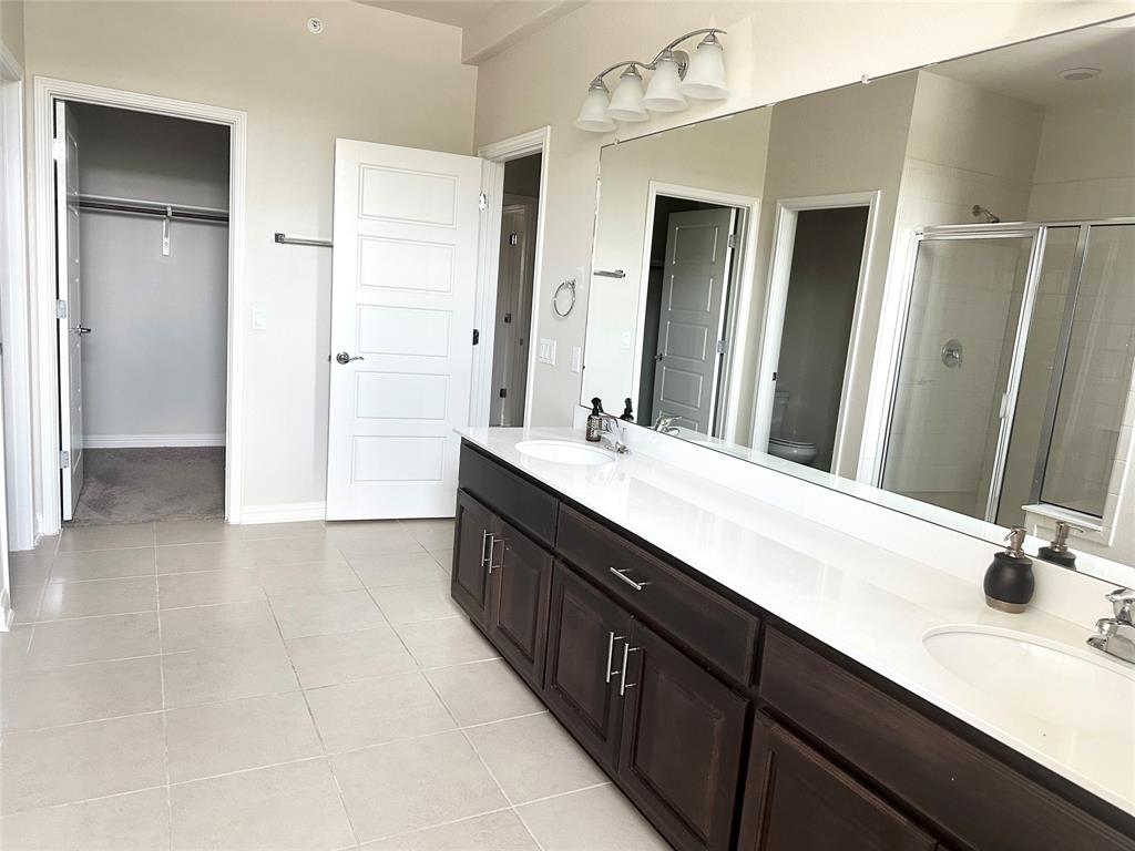 6814 East Riverside Drive, Unit 26 Austin, TX 78741 - Photo 11 of 21 A contemporary primary bathroom featuring a dual vanity, sleek white countertops, and a spacious glass-enclosed shower.
