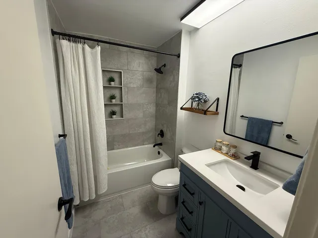a bathroom with a double vanity sink toilet mirror and shower