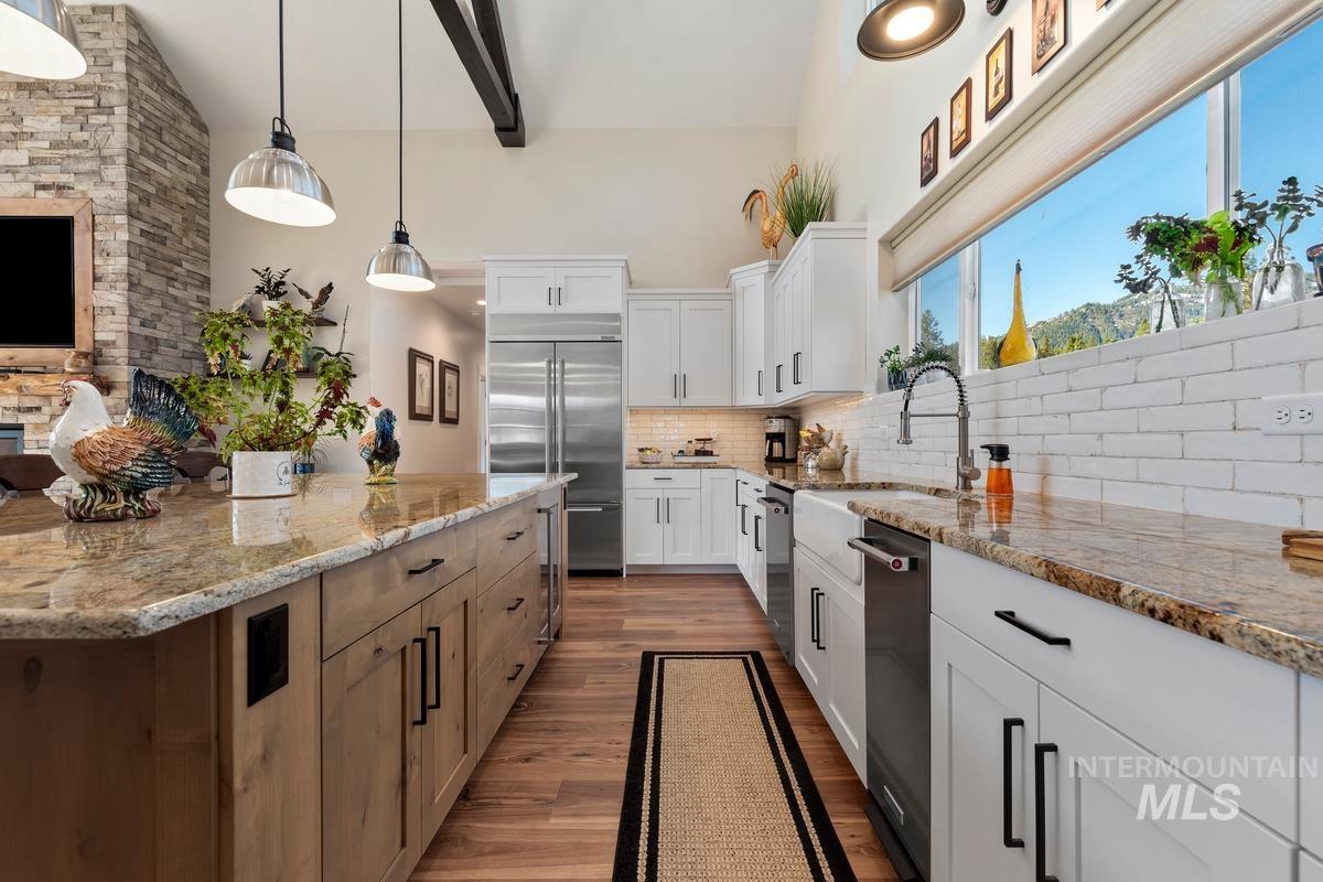 21 Open Road Garden Valley, ID 83622 - Photo 10 of 49 Dual tone kitchen with dual tone cabinets, light stone counters, stainless steel appliances, dark wood-style flooring, and vaulted ceiling
