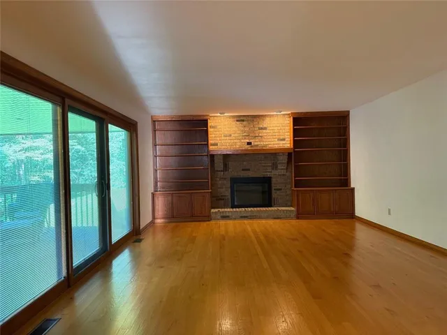 a view of empty room with wooden floor and fireplace