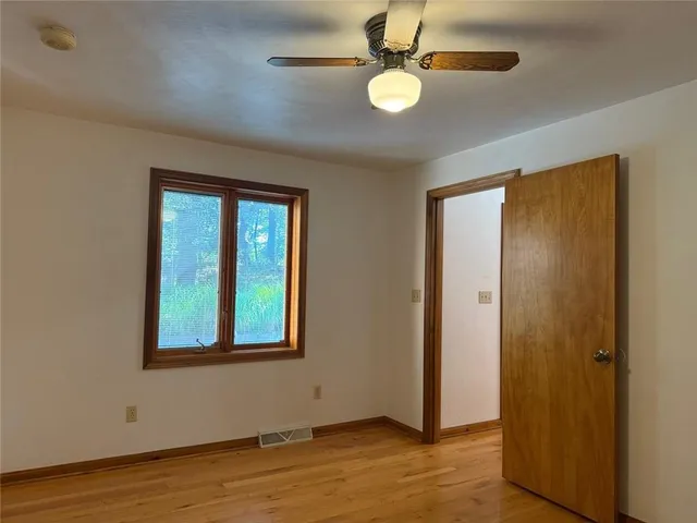 a view of an empty room with wooden floor and a window