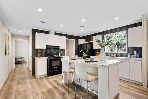 a kitchen with a sink a stove a refrigerator and white cabinets