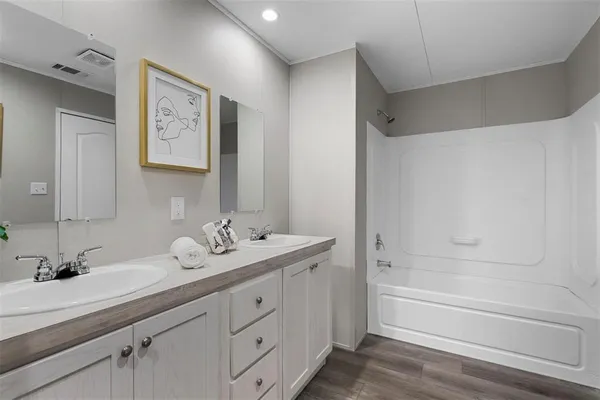 a bathroom with a sink double vanity granite tub and a mirror