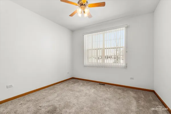 an empty room with a window and a fan