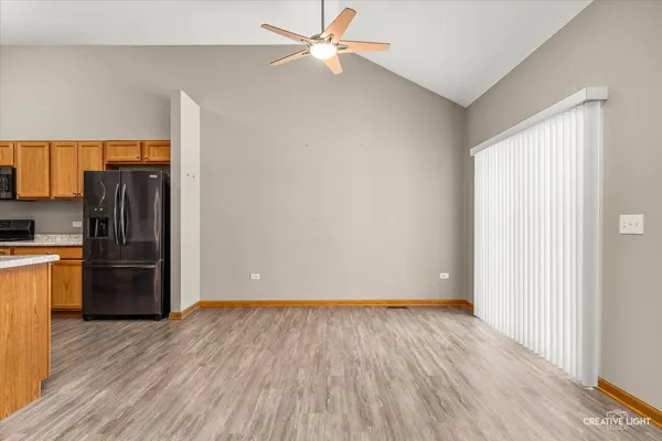 a view of a kitchen with wooden floor a ceiling fan and refrigerator in a kitchen