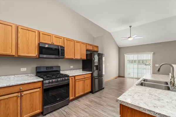 a kitchen with granite countertop a stove top oven a sink dishwasher and wooden cabinets with wooden floor