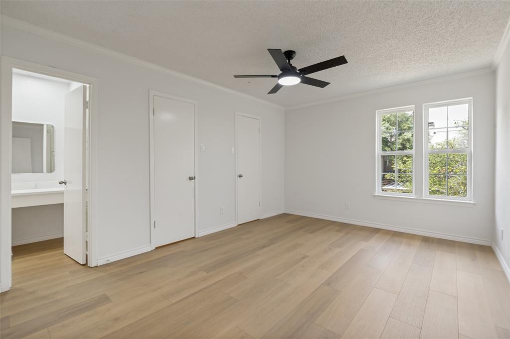 5300 Keller Springs Road, Unit 2042 Dallas, TX 75248 - Photo 19 of 28 Spacious room featuring wood-finish flooring, two large windows, a ceiling fan with integrated lighting, and multiple closet doors